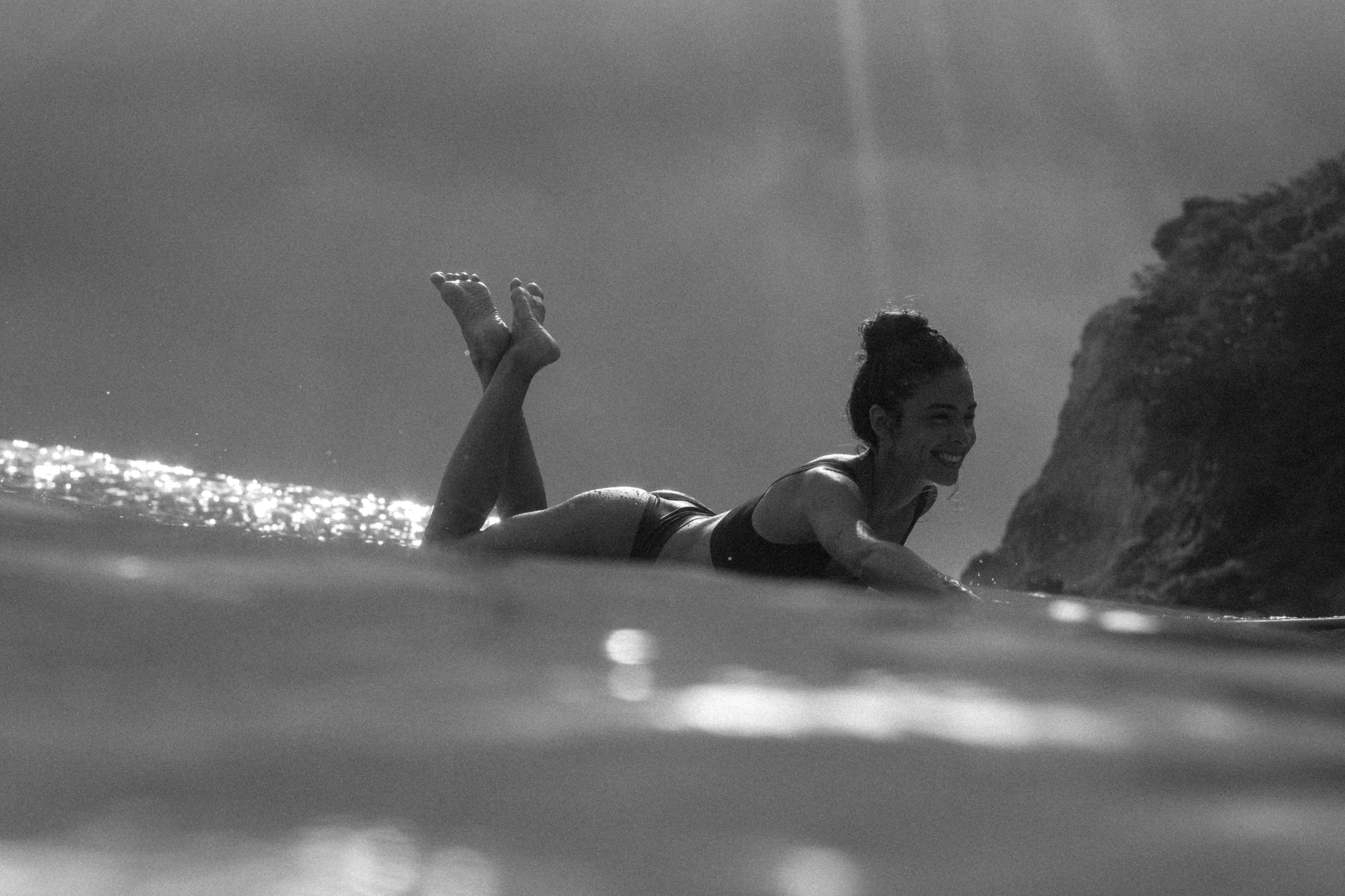 Mulher deitada numa prancha no mar, em preto e branco
