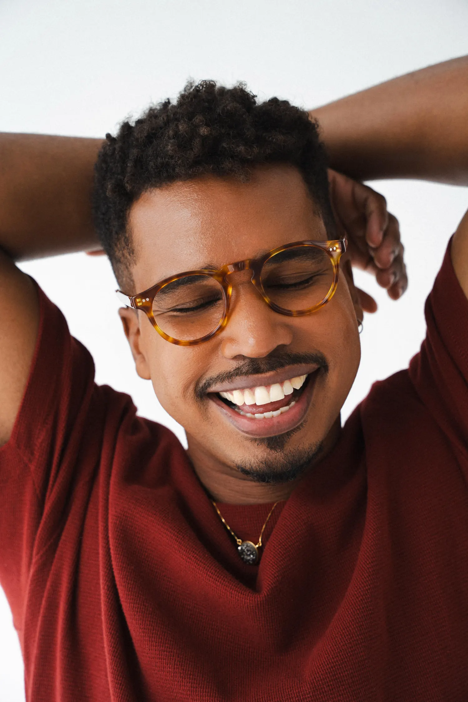 Homem de óculos sorrindo com as mãos atrás da cabeça