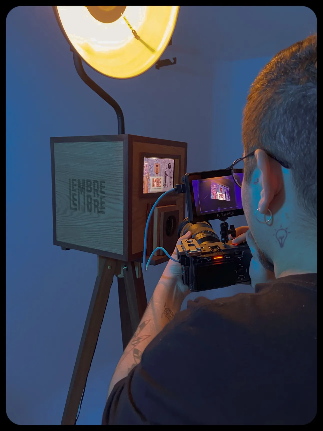 Pessoa filmando uma cabine de madeira iluminada por um refletor
